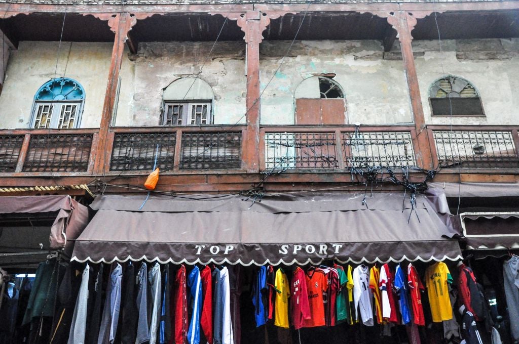 Old mixes with new in the mellah of Fez: Former Jewish homes, with outward-facing balconies, with t-shirt shops below them. (photo credit: Michal Shmulovich)