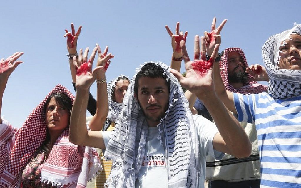 Israelis wearing keffiyehs hold up hands covered in fake blood to protest the release of Palestinian prisoners near the prime minister's office, July 28, 2013 (photo credit: Flash90) Israelis wearing keffiyehs hold up hands covered in fake blood to protest the release of Palestinian prisoners near the prime minister's office, July 28, 2013 (photo credit: Flash90)