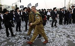 IDF soldiers walk by ultra-Orthodox Jews preparing for a massive protest against plans to introduce compulsory military service, March 2, 2014  (Yonatan Sindel/FLASH90)