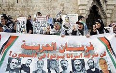 Palestinian protesters hold posters and banners with portraits of Palestinians jailed in Israeli prisons on Saturday, March 8, 2014, during a demonstration calling for their release at the Damascus Gate in Jerusalem's Old City (photo credit: Sliman Khader/Flash90)