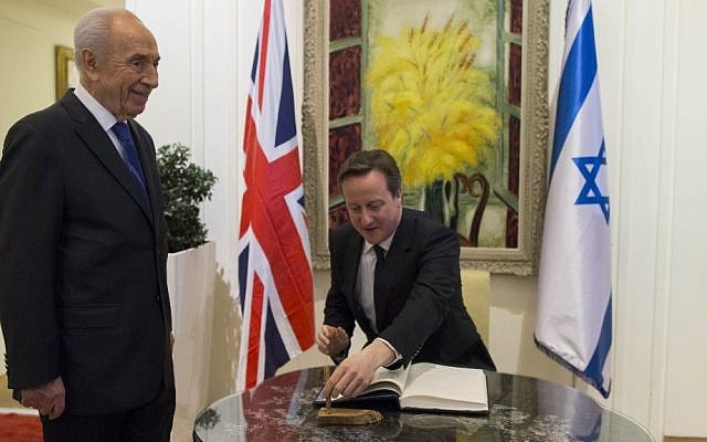 British Prime Minister David Cameron signs the visitors book at the President's Residence while President Shimon Peres looks on, March 12, 2014 (photo credit: Yonatan Sindel/Flash90)
