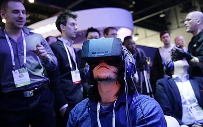 Attendees play a video game wearing Oculus Rift virtual-reality headsets at the Intel booth at the International Consumer Electronics Show (CES), in Las Vegas, 2014. (photo credit: AP/Jae C. Hong, File)