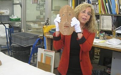 Dr. Debby Hershman, curator of prehistoric culture at the Israel Museum, holds up a neolithic mask in the museum's laboratories. (photo credit: Ilan Ben Zion/Times of Israel staff) Dr. Debby Hershman, curator of prehistoric culture at the Israel Museum, holds up a neolithic mask in the museum's laboratories. (photo credit: Ilan Ben Zion/Times of Israel staff)