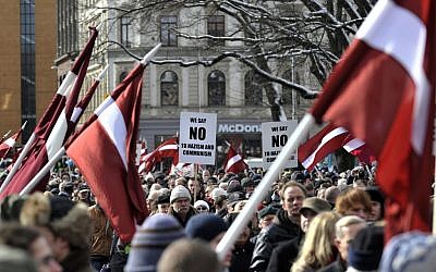 People carry Latvian flags as they march to the Freedom Monument to commemorate World War II veterans who fought in Waffen SS divisions, in Riga, Latvia, Sunday, March 16, 2014. (photo credit: AP/Roman Kosarov, F64 Photo Agency)