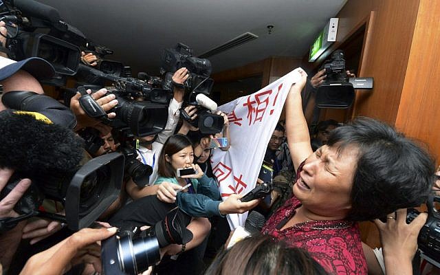 A Chinese relative of passengers aboard a missing Malaysia Airlines plane cries as she holds a banner in front of journalists reading 'We are against the Malaysian government for hiding the truth and delaying the rescue. Release our families unconditionally!" at a hotel in Sepang, Malaysia, Wednesday, March 19, 2014. Malaysian authorities examined new radar data from Thailand that could potentially give clues on how to retrace the course of the Malaysia Airlines plane that vanished early March 8 with 239 people aboard en route from Kuala Lumpur to Beijing. Twenty-six countries are looking for the aircraft as relatives anxiously await news. (photo credit: AP Photo) A Chinese relative of passengers aboard a missing Malaysia Airlines plane cries as she holds a banner in front of journalists reading 'We are against the Malaysian government for hiding the truth and delaying the rescue. Release our families unconditionally!" at a hotel in Sepang, Malaysia, Wednesday, March 19, 2014. Malaysian authorities examined new radar data from Thailand that could potentially give clues on how to retrace the course of the Malaysia Airlines plane that vanished early March 8 with 239 people aboard en route from Kuala Lumpur to Beijing. Twenty-six countries are looking for the aircraft as relatives anxiously await news. (photo credit: AP Photo)