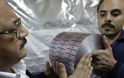 Adel Abd ElSadk, left, examines a final product, aluminum foil printed with the drug name and brand, at his factory financed partly from the Social Development Fund outside Cairo, Egypt. Monday, March 3, 2014 (Photo credit: Amr Nabil/AP)