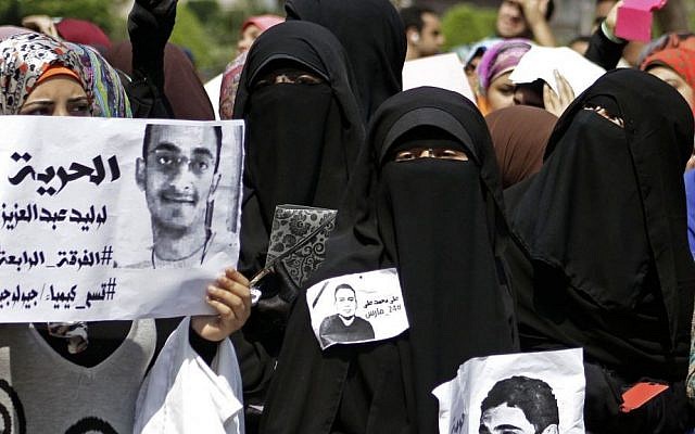 A supporter of ousted President Mohammed Morsi holds a poster, left, with Arabic that reads, "freedom to Waleed Abdel Aziz, fourth team, faculty of chemistry, geology," during a demonstration inside Cairo University in Egypt on Monday, March 24, 2014. (photo credit: AP Photo/Ahmed Abd El Latef, El Shorouk) A supporter of ousted President Mohammed Morsi holds a poster, left, with Arabic that reads, "freedom to Waleed Abdel Aziz, fourth team, faculty of chemistry, geology," during a demonstration inside Cairo University in Egypt on Monday, March 24, 2014. (photo credit: AP Photo/Ahmed Abd El Latef, El Shorouk)