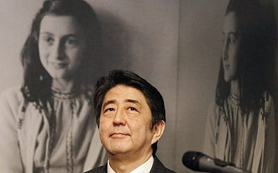 Japan's Prime Minister Shinzo Abe looks at pictures of Anne Frank, rear, as he visits the Anne Frank House museum in Amsterdam, Netherlands, Sunday, March 23, 2014. Abe expressed regrets that 300 copies of Anne Franks' diary were vandalized recently in Tokyo libraries. (photo credit: AP/Frank Augstein)