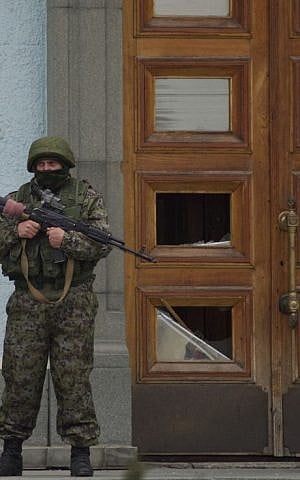 An unidentified man guards the entrance to a local government building in Simferopol, Ukraine, on Saturday, March 1, 2014. (AP Photo/Ivan Sekretarev)