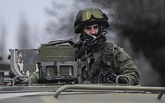 A man in unmarked uniform looks from atop of a military vehicle while standing guard as troops taking control the the Coast Guard offices in Balaklava, outskirts of Sevastopol, Ukraine, Saturday, March 1, 2014 (photo credit: AP/Andrew Lubimov)