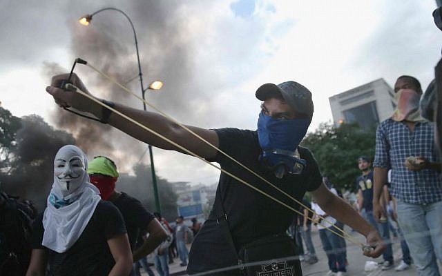A man shoots a slingshot at national guard troops following one of the largest anti-government demonstrations yet on March 2, 2014 in Caracas, Venezuela. (John Moore/Getty Images/JTA)