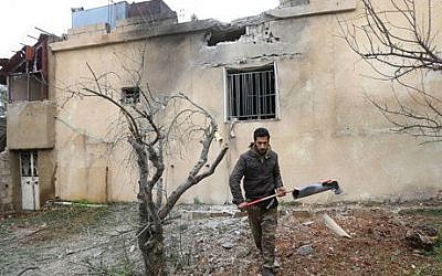 A Lebanese man holds part of an exploded rocket that hit a house in the predominately Shiite town of Labweh, near the border with Syria, northeast Lebanon, Monday March 17, 2014 (photo credit: AP/Hussein Malla)