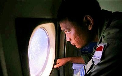 An Indonesian Navy crew member scans the water bordering Indonesia, Malaysia and Thailand during a search operation for the missing Malaysian Airlines Boeing 777 near the Strait of Malacca on Monday, March 10, 2014. (photo credit: AP/Binsar Bakkara)