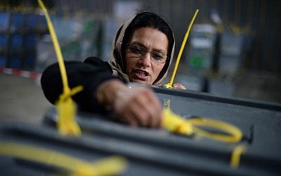 An Afghan election commission worker takes notes of serial numbers of ballot boxes at a counting centre at a warehouse in Kabul on April 6, 2014. (photo credit: AFP/Wakil KOHSAR)