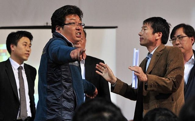 A relative (2nd L) of a passenger on board a capsized ferry argues with South Korean government officials as the officials try to brief them on the rescue situation, at a gym in Jindo on April 17, 2014.  (photo credit: AFP/ JUNG YEON-JE)