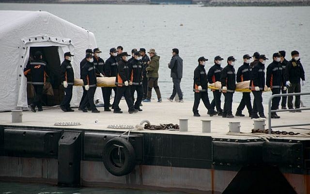 The bodies of victims recovered from the "Sewol" ferry are carried to waiting ambulances at Jindo harbor on April 22, 2014. (photo credit: AFP Photo/Ed Jones) The bodies of victims recovered from the "Sewol" ferry are carried to waiting ambulances at Jindo harbor on April 22, 2014. (photo credit: AFP Photo/Ed Jones)
