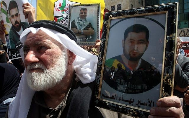 A Palestinian man holds up a portrait of a relative during a demonstration to mark Prisoners Day in Hebron, on April 17, 2014. (photo credit: AFP/Hazem Bader)
