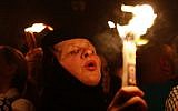 A Christian Orthodox worshipper holds a candle lit from the "Holy Fire" as thousands gather in the Church of the Holy Sepulcher in Jerusalem's old city on April 19, 2014 (Photo credit: Gali Tibbon/AFP)
