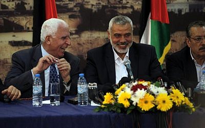 Palestinian Fatah delegation chief Azzam al-Ahmed, left, laughs with Hamas Prime Minister in the Gaza Strip Ismail Haniyeh during a press conference in Gaza on Wednesday (photo credit: AFP/Said Khatib)