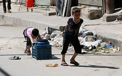 Children carry a cylinder of water in a street of the Syrian city of Aleppo on April 17, 2014. (photo credit: AFP/ALEPPO MEDIA CENTRE/ZEIN AL RIFAI)