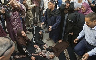 Egyptian women faint outside the courtroom in Egypt's southern province of Minya after an Egyptian court sentenced Muslim Brotherhood leader Mohamed Badie and other alleged Islamists to death, on April 28, 2014. (photo credit: AFP Photo/Khaled Desouki)