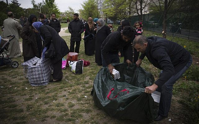 Syrian refugees pack goods on April 21, 2014 in the Edouard Vaillant parc in Saint-Ouen, north of Paris, where they spend most of their days awaiting housing solutions (photo credit: AFP/Joel Saget) Syrian refugees pack goods on April 21, 2014 in the Edouard Vaillant parc in Saint-Ouen, north of Paris, where they spend most of their days awaiting housing solutions (photo credit: AFP/Joel Saget)