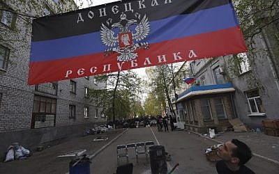 A man looks at a flag of a self-proclaimed Donetsk republic in front of a captured police station on April 19, 2014 in Slavyansk (photo credit: AFP/Max Vetrov)