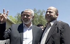 Then-Hamas Prime Minister in the Gaza Strip Ismail Haniyeh (L) flashes the V-sign as he greets the movement's deputy leader, Moussa Abu Marzuk, upon his arrival in Gaza City, on Monday, April 21, 2014 (photo credit: AFP Photo/Mahmud Hams)