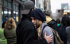 Tom Duggan hugs Sarah Rogo, who said they were both present last year at the marathon, while a billboard television screen broadcasts the ceremony commemorating the one year anniversary of the 2013 Boston Marathon Bombing , on April 15, 2014 in Boston, Massachusetts. (Andrew Burton/AFP)
