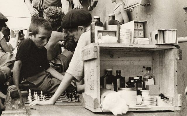 Ruth Gruber. Children playing chess on the refugees’ deck of the Henry Gibbins next to an outdoor medical station and pharmacy, 1944. (© Ruth Gruber) Ruth Gruber. Children playing chess on the refugees’ deck of the Henry Gibbins next to an outdoor medical station and pharmacy, 1944. (© Ruth Gruber)