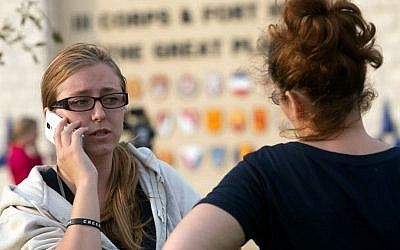 Krystina Cassidy, left, and Dianna Simpson attempt to make contact with their husbands who are stationed inside Fort Hood while standing outside of the Bernie Beck Gate on Wednesday, April 2, 2014, in Fort Hood, Texas. (photo credit: AP/Tamir Kalifa)
