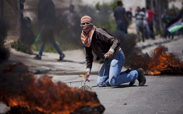 A masked Palestinian takes cover during a protest calling for the release of Palestinian prisoners held in Israeli jails, outside Ofer, an Israeli military prison near the West Bank city of Ramallah, Friday, April 4, 2014. (photo credit: AP Photo/Majdi Mohammed) A masked Palestinian takes cover during a protest calling for the release of Palestinian prisoners held in Israeli jails, outside Ofer, an Israeli military prison near the West Bank city of Ramallah, Friday, April 4, 2014. (photo credit: AP Photo/Majdi Mohammed)