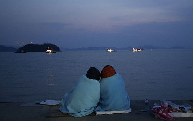 Relatives of passengers aboard the sunken ferry Sewol sit near the sea at a port in Jindo, south of Seoul, South Korea, Sunday, April 20, 2014. (AP Photo/Lee Jin-man)