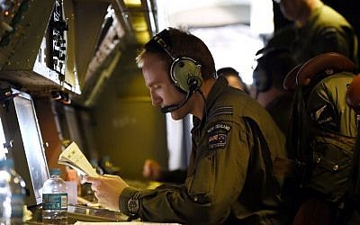 Flight Lieutenant Stephen Graham studies notes aboard a Royal New Zealand Air Force (RNZAF) P-3 Orion on route to search over the southern Indian Ocean looking for debris from missing Malaysia Airlines flight MH370 Friday, April 11, 2014. (AP Photo/Richard Polden)