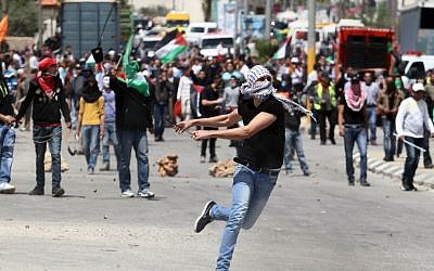 A Palestinian man uses a slingshot to hurl a stone towards Israeli soldiers during clashes outside Israel's Ofer military prison, in the West Bank, April 4, 2014. (photo credit: Issam Rimawi/Flash90)
