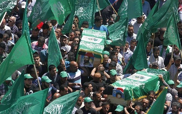 Palestinian mourners wave the green flag of the Islamist movement Hamas as they attend the funeral of two Hamas members, Adel and Imad Awadallah, killed by Israeli forces in 1998, after Israel returned the remains of Palestinian militants to their families for burial, on April 30, 2014. (photo credit: Issam Rimawi/FLASH90) Palestinian mourners wave the green flag of the Islamist movement Hamas as they attend the funeral of two Hamas members, Adel and Imad Awadallah, killed by Israeli forces in 1998, after Israel returned the remains of Palestinian militants to their families for burial, on April 30, 2014. (photo credit: Issam Rimawi/FLASH90)