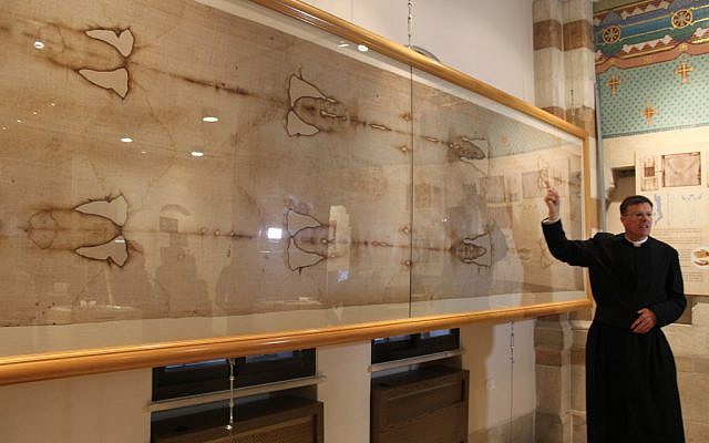 Father Eamon Kelly discusses a full-size replica of the Shroud of Turin (photo credit: Rebecca McKinsey/Times of Israel)