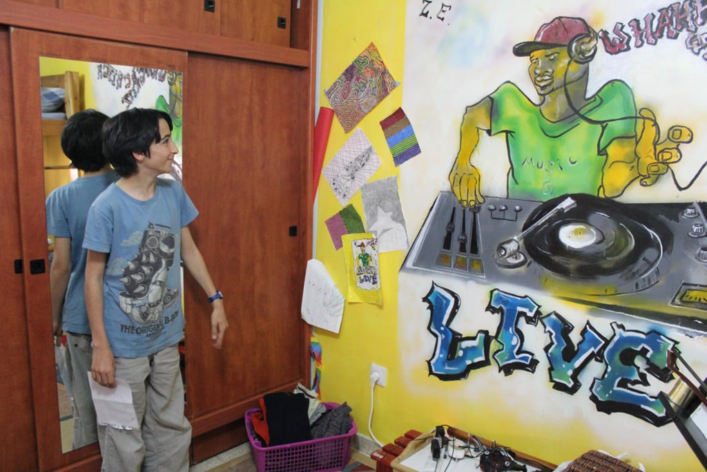 Inbar Elnatan, 12, shares a room with his older brother, Rotem. The walls are covered with a mural their father painted that plays to Rotem's love of DJing, as well as pictures Inbar has drawn. (The Times of Israel/Rebecca McKinsey) 