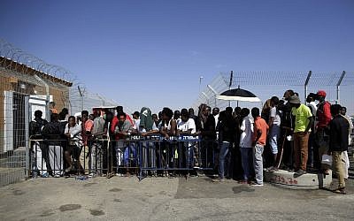 African migrants enter the Holot detention center, southern Israel, Friday, April 11, 2014. Hundreds of African migrants gathered outside the Holot detention center in Israel’s Negev desert on Friday to eat matzo and recall the Passover story - one of freedom from bondage - mere steps away from a detention facility where they are being held. (photo credit: AP/Tsafrir Abayov)