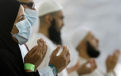 Egyptian Muslim pilgrims, some wearing masks as a precaution against the Middle East respiratory syndrome, pray during the hajj, in Mina near the Muslim holy city of Mecca, Saudi Arabia in 2013.  (photo credit: AP/Amr Nabil, File)