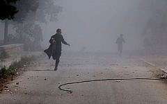 Syrian residents running in the street after a government warplane dropped barrel bombs on the al-Sakhour neighborhood of Aleppo, Syria, on Saturday, April 5, 2014. (photo credit: AP/Aleppo Media Center, AMC/File)