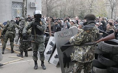 Armed pro-Russian activists occupy the police station carrying riot shields as people watch on, in the eastern Ukraine town of Slovyansk on Saturday, April 12, 2014. Pro-Moscow protesters have seized a number of government buildings in the east over the past week, undermining the authority of the interim government in the capital, Kiev. (photo credit: AP/Efrem Lukatsky)