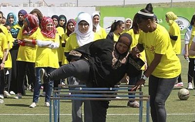 American track and field great Jackie Joyner-Kersee helps a Palestinian woman over a hurdle in the West Bank city of Ramallah, Thursday, April 17, 2014. (photo credit: AP Photo/Nasser Shiyoukhi)