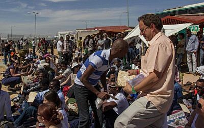 Abramowitz handing out matzahs at a seder for African asylum seekers, April 2014. (photo credit: Jacob Ross)