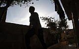 In this Sunday, Nov. 3, 2013 photo, a Palestinian boy walks around his home in the village of Beit Ummar near the West Bank city of Hebron. At the age of 15, the boy was held for nine months in an Israeli military jail for throwing rocks at passing Israeli cars near his village in the West Bank.  (AP Photo/Majdi Mohammed)