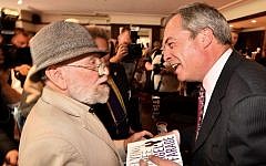 UK Independence Party (UKIP) leader Nigel Farage (R) smiles after signing a copy of his book for a supporter in Basildon in Essex, east of London, on May 23, 2014, as results continue to come in from local council elections in Britain. (photo credit: Ben Stansall/AFP)