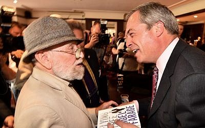 UK Independence Party (UKIP) leader Nigel Farage (R) smiles after signing a copy of his book for a supporter in Basildon in Essex, east of London, on May 23, 2014, as results continue to come in from local council elections in Britain. (photo credit: Ben Stansall/AFP)