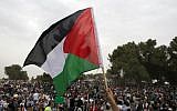 Illustrative photo of a protester holding up a Palestinian flag (AFP/Ahmad Gharabli)