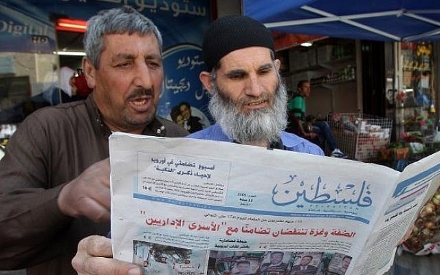 Palestinian men read the Hamas-affiliated newspaper Falastin (Palestine) in a street of the West Bank town of Hebron on May 10, 2014. (photo credit: Hazem Bader/AFP) Palestinian men read the Hamas-affiliated newspaper Falastin (Palestine) in a street of the West Bank town of Hebron on May 10, 2014. (photo credit: Hazem Bader/AFP)