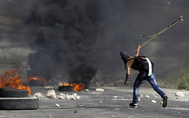 A masked Palestinian demonstrator uses a slingshot to hurl a stone at Israeli security forces outside Ofer prison in the West Bank village of Beitunia, on May 16, 2014. (photo credit: AFP/Abbas Momani) A masked Palestinian demonstrator uses a slingshot to hurl a stone at Israeli security forces outside Ofer prison in the West Bank village of Beitunia, on May 16, 2014. (photo credit: AFP/Abbas Momani)
